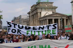 Gruppe von Schülern, die in Berlin mit einem bunt bemalten "Students for Future"-Schild marschiert