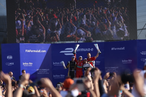 Podium mit einer Gruppe von Menschen, die Pokale halten, Hintergrund zeigt "FIA Formula E Mexico City" Branding und einen Bildschirm.