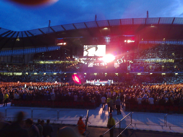 Ein Konzertsaal mit Menschen, Scheinwerfern und einer Projektionsfläche.