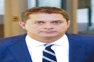 Ein Mann im Anzug und Krawatte geht einen Flur entlang und sieht besorgt aus, möglicherweise wegen einer Vergewaltigungsanklage, mit einem unscharfen Hintergrund.