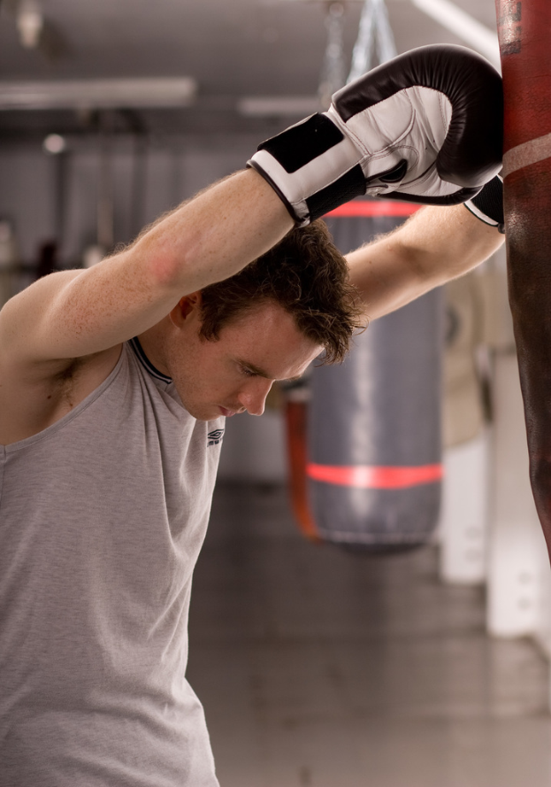 Eine Person mit Handschuhen steht vor einem Boxobjekt, mit einem weiteren Boxobjekt und verschiedenen anderen Objekten im Hintergrund, unter einer Decke und über einem Boden.