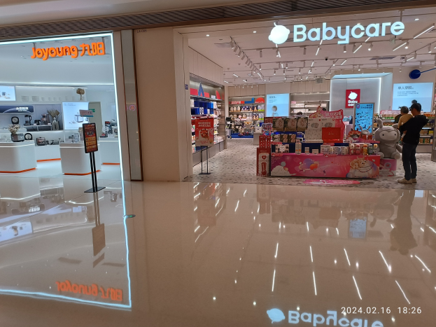 Babybedarfsladen im Mall of Asia, mit Menschen, die sich Spielzeug und Artikel anschauen, die auf Gestellen unter Deckenlampen präsentiert werden.