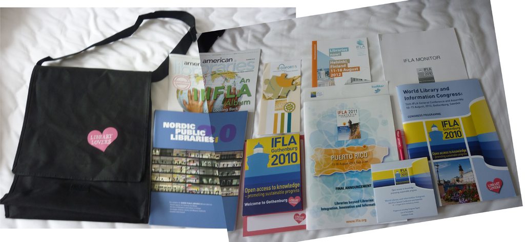 Eine Tasche mit "Bibliotheksliebhaber" drauf und einige Bücher auf einem Bett.