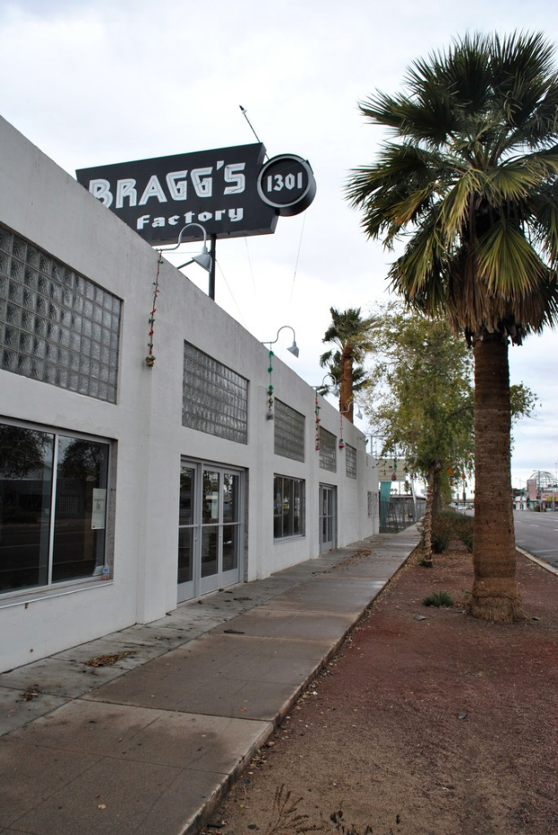 Ein Gebäude mit einem Banner, auf dem "Braggs Factory" steht, umgeben von Bäumen.