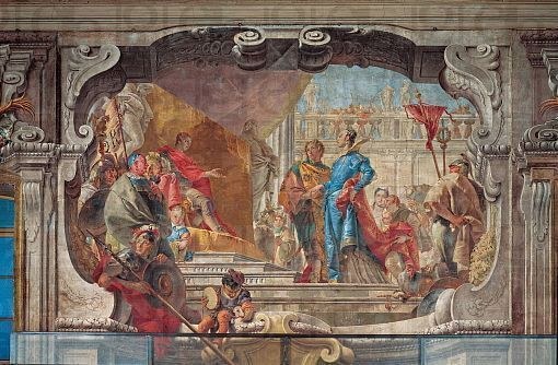 Ein lebendiges und detailliertes Fresko an einer Decke, das eine Gruppe von Menschen, Skulpturen und Gegenstände in einem realistischen Stil mit variabler traditioneller und moderner Kleidung zeigt, die Bewegung und Leben vermittelt.