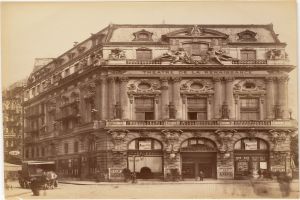 Altes Foto des Théâtre de la Renaissance in Paris mit seiner prächtigen Fassade mit Fenstern, Säulen, Bögen und Skulpturen, mit ein paar Menschen und Fahrzeugen im Vordergrund und dem Himmel im Hintergrund.