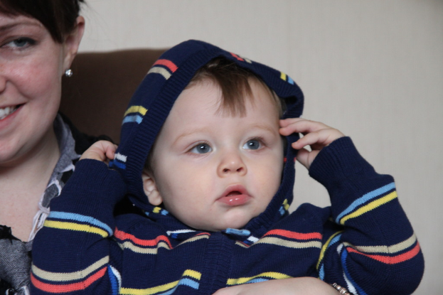 Eine Frau hält ein Kind in den Armen und steht vor einer Wand.