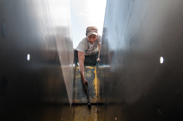 Ein Mann in einem T-Shirt, Hose und einer Mütze schlägt mit einem Hammer auf ein Objekt ein.
