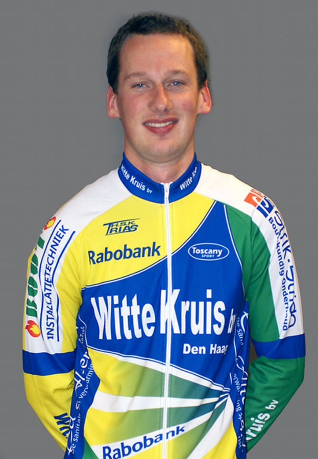 Ein Sportler posiert für ein Foto und trägt ein Hemd mit mehreren Namen von Sponsorunternehmen.