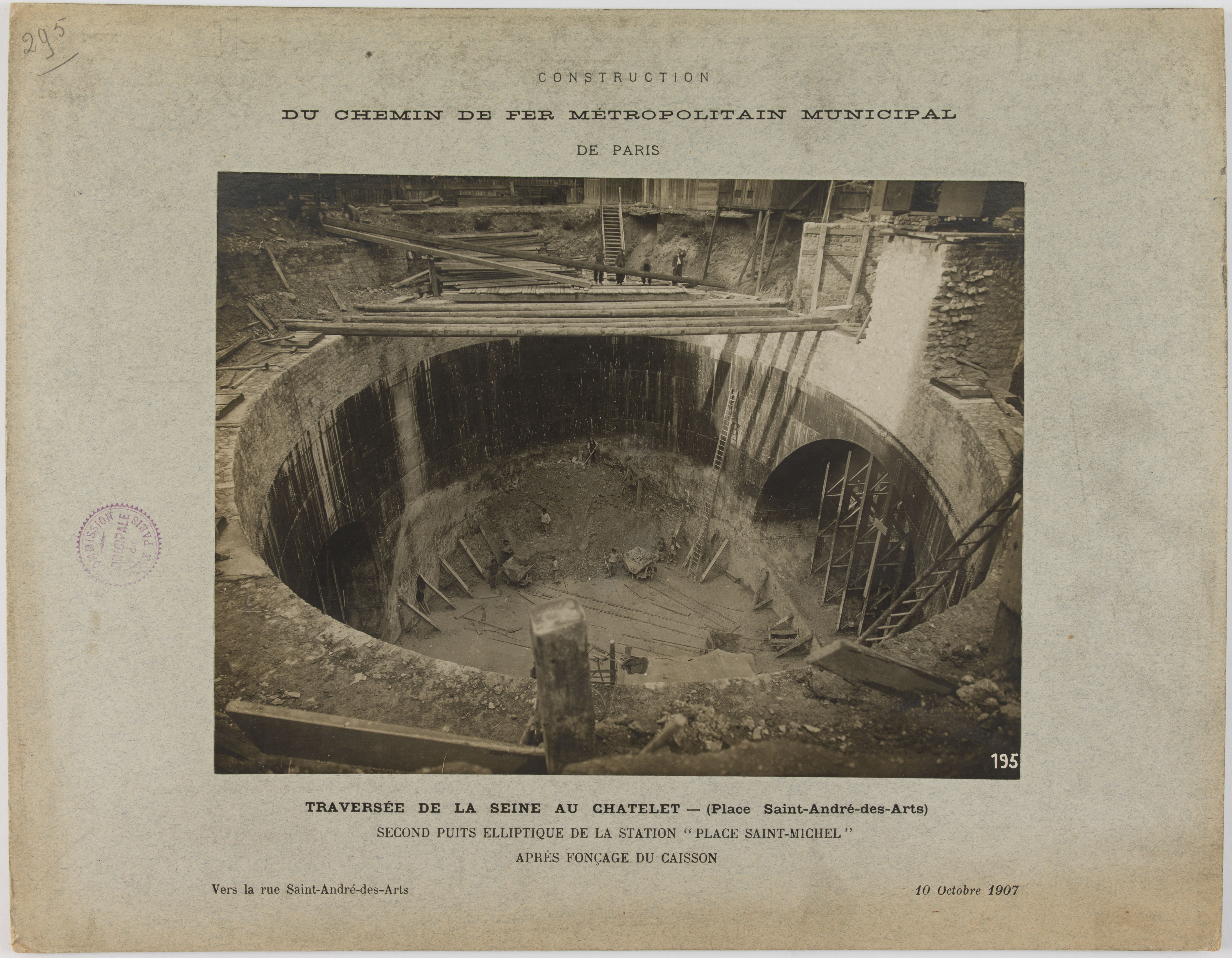 Ein altes Schwarz-Weiß-Foto eines Tunnels im Bau, mit einem Stempel auf der linken Seite und Text unten.