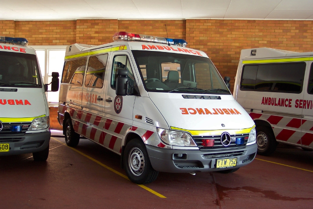 Ein weißer Krankenwagen steht vor einer Backsteinwand.