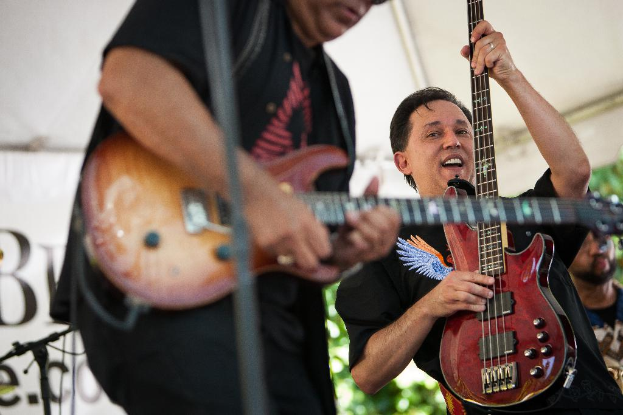 Eine Gruppe von Menschen, die braune Musikinstrumente halten und in ein Mikrofon singen.