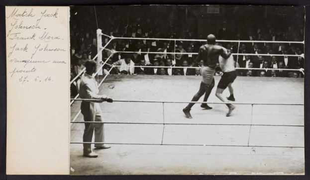 Schwarz-weißes Foto von zwei Boxern im Ring mit einem Schiedsrichter links und Zuschauern im Hintergrund, betitelt mit "Jack Johnson vs Frank Morgan".