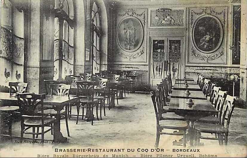 Schwarz-weiß-Foto eines alten Brasserie-Restaurant-Interieurs im Coq d'or, Bordeaux, Frankreich, mit Tischen, Stühlen, Wandgemälden, einer zentralen Tür und Text am unteren Rand.
