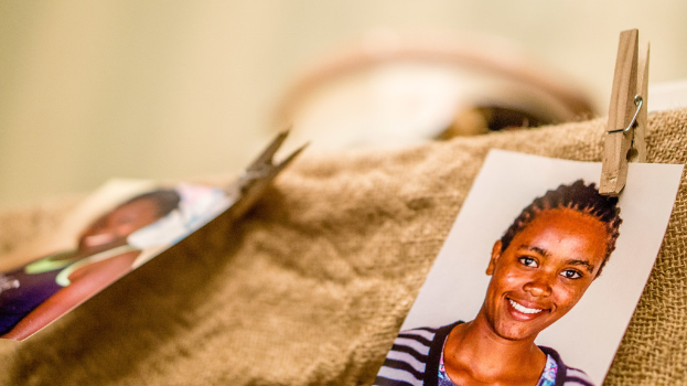 Auf einem Tisch befinden sich eine Klammer, ein Passfoto im Passformat und ein Stoffstück auf der rechten Seite; links und im Hintergrund ist alles unscharf.