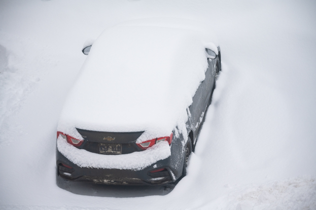 Ein schneebedecktes Auto am Straßenrand.