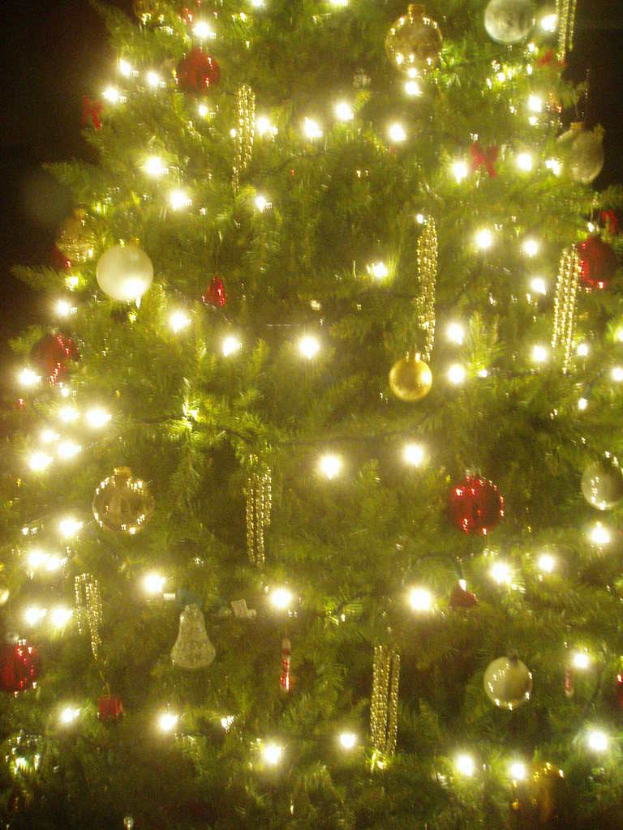 Ein Weihnachtsbaum mit Lichtern, Schmuck und anderen Dekorationen.