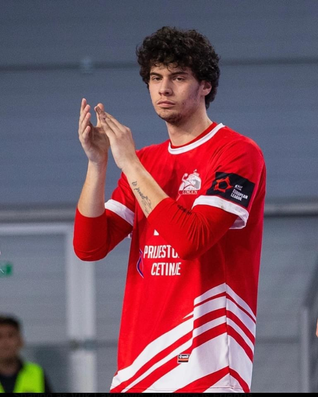 Ein Mann in rot-weißem T-Shirt klatscht in der Vordergrund, während im Hintergrund eine weitere Person und eine Wand zu sehen sind. Unten steht der Text "Copenhagen Futsal Club - Foto 1".