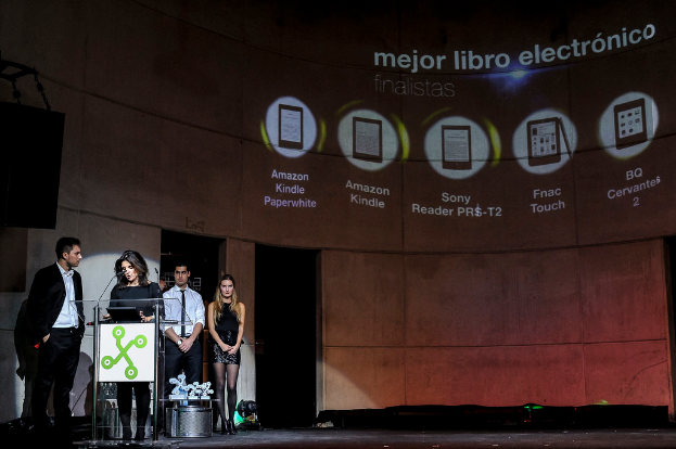 Vier Personen stehen links, wobei eine Frau ein Seminar hält und im Hintergrund Bilder von Gadgets mit ihren Namen darunter zu sehen sind.