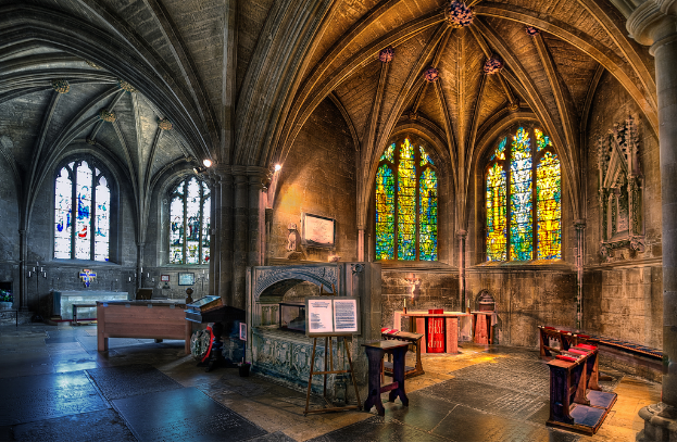 Ein Raum mit Tischen, Bänken, einer Tafel, Fenstern, einem Kamin, Kerzen und Lichtern in der Mitte, bearbeitet.