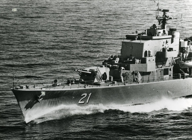 Ein Schwarz-Weiß-Foto eines großen Lenkwaffenfregatts mit einer sichtbaren Identifikationsnummer, das auf dem Wasser fährt.