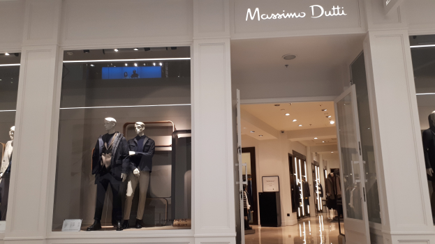 Innenansicht des Massimo Dutti-Ladens in Mailand, Italien, mit Schaufensterpuppen in aktueller Mode, beleuchteter Decke, Informationsschildern und sichtbarem Boden.