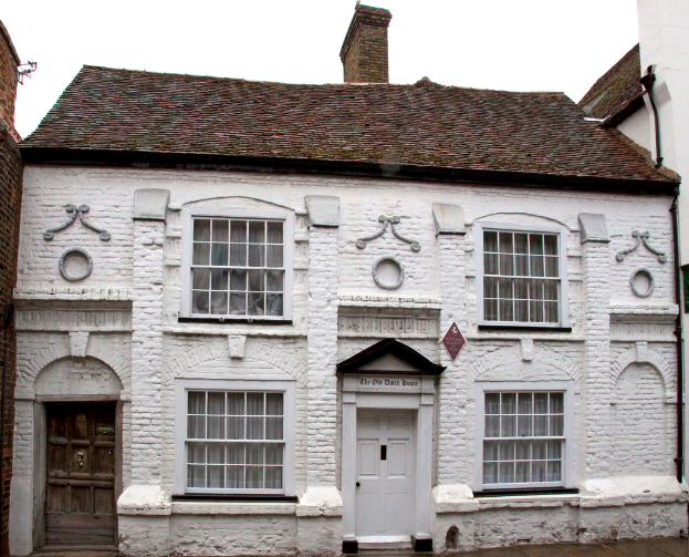 Ein weißes Haus mit einem braunen Dach und einem Schornstein.