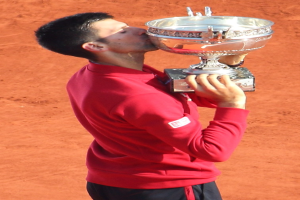 Novak Djokovic feiert mit dem French-Open-Pokal nach dem Sieg gegen Rafael Nadal im Finale der Herren-Einzel, hält und küsst den Pokal mit einem triumphierenden Gesichtsausdruck.
