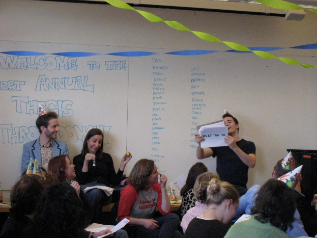 Eine Gruppe von Menschen feiert ihren ersten jährlichen Thesendurchwurf, mit Bändern auf dem Dach und einigen Personen mit Kappen.