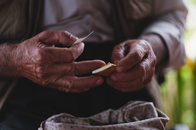 Alter Mann hält ein Blatt Papier in der Hand und sieht besorgt aus, mit einem unscharfen Hintergrund, möglicherweise aufgrund von Demenz.