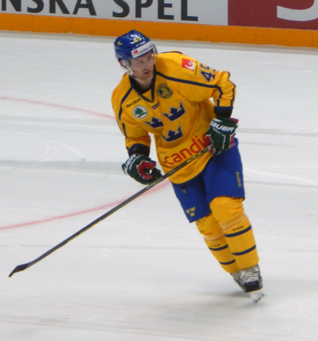 Eishockeyspieler in Bewegung auf dem Eis, der einen Helm, Handschuhe und Schlittschuhe trägt und einen Hockeystock hält, mit einer Texttafel im Hintergrund.