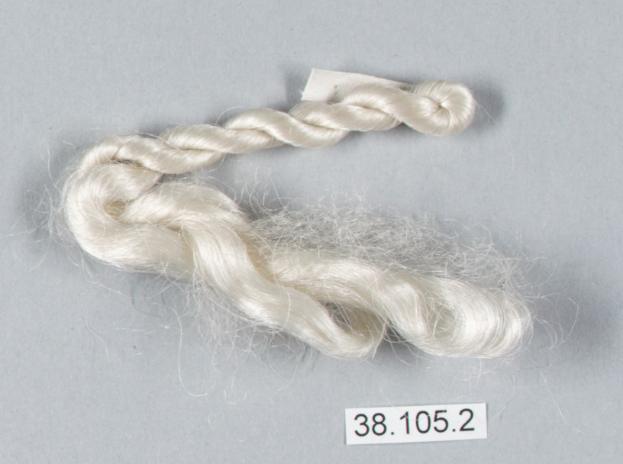 Ein Faden weißer Seidenfaden mit einer darauf geschriebenen Zahl auf einer grauen Oberfläche.