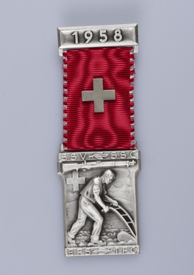 Silberne Medaille mit roter Schleife, eingraviert mit "1958", zeigt eine Person, die ein Objekt hält, verliehen an Schweizer Armeeangehörige für ihren Dienst im Zweiten Weltkrieg.
