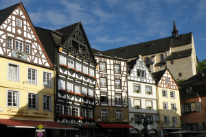 Eine Reihe von Fachwerkhäusern in Rothenburg ob der Tauber, Deutschland, mit Fenstern, umgeben von Bäumen unter einem klaren blauen Himmel.
