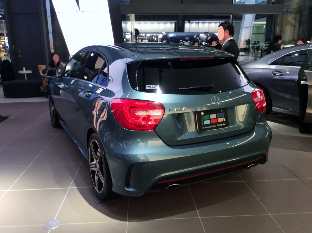 Ein Mercedes-Benz A-Klasse Hatchback auf der IAA in Frankfurt, glänzend schwarz mit Chromakzenten, niedriger Profil, breite Basis, markantes Kühlergrill und Aluminiumräder, umgeben von einer Gruppe von Menschen.