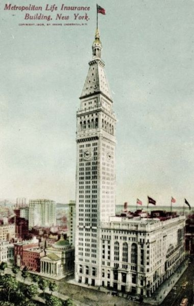 Schwarz-weiß-Postkarte des Metropolitan Life Insurance Building in New York City, die eine belebte städtische Szene mit mehreren Gebäuden, Bäumen und Fahrzeugen auf der Straße sowie den Text "Metropolitan Life Insurance" oben zeigt.