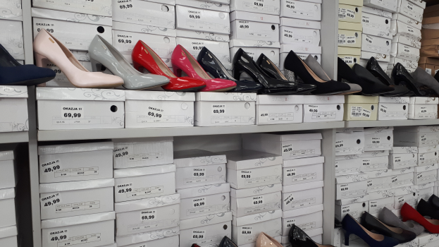 Ein Regal voller verschiedener Schuharten in Kartons, jeweils mit einem Preisschild, und Kartons aus Pappe auf der rechten Seite.