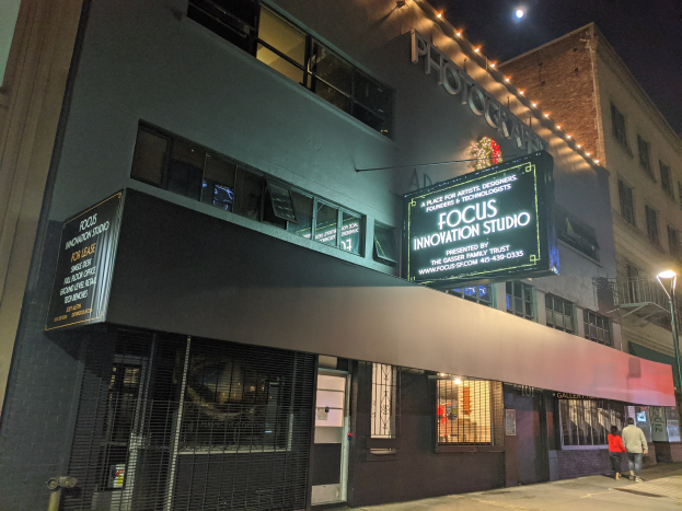 Außenansicht des Focus Innovation Studio in New York City bei Nacht, mit beleuchteten Fenstern, Namensschildern und Passanten auf dem Gehweg gegen einen sichtbaren Nachthimmel.