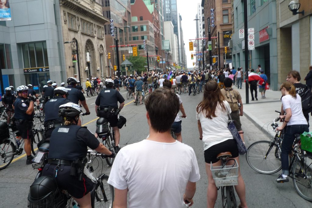 Gebäude säumen eine Straße, auf der einige Menschen Fahrräder fahren.