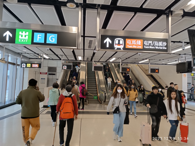 Eine Gruppe von Menschen mit Gep├Ąck geht durch einen Flughafen mit Rolltreppen, Texttafeln, Deckenlampen und Glasw├Ąnden im Hintergrund, mit einem Wasserzeichen, das den Flughafen aufgrund der Coronavirus-Pandemie als geschlossen kennzeichnet.