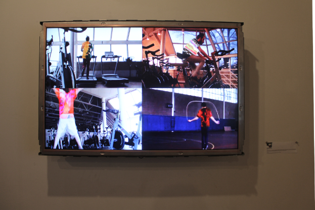 Ein an der Wand montierter Fernseher, auf dem Menschen Sport treiben