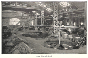 Schwarzes und weißes Foto eines Fabrikinneren mit Arbeitern, die Maschinen bedienen, Metallstangen und -pole, mit der Beschriftung "Neue Eisenglebeerei, die erste Fabrik in Deutschland" unten.