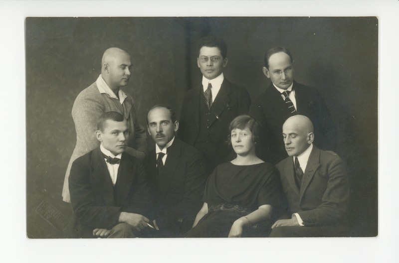 Ein Schwarz-Weiß-Foto einer Gruppe von Menschen in Blazern, Krawatten und Hemden, die für ein Foto posieren.